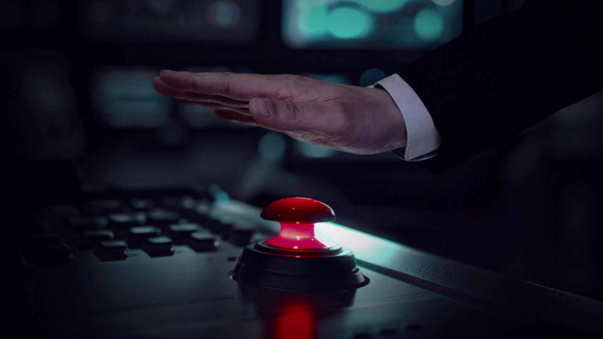 A hand poised above a glowing red button in the announcement trailer